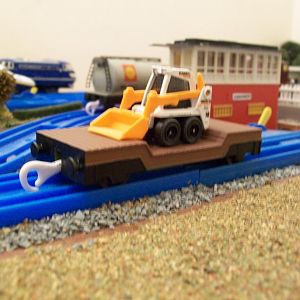 Re-painted Plarail Lowmac wagon, with a Matchbox, skid steer shovel load. 
The Lowmac is a standard Tomy Thomas model, which came in green livery (th